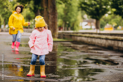 Mother with daughter having fun jumping in puddles