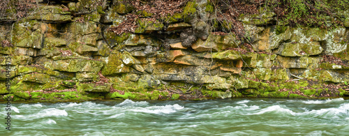 A stone wall on the bank of the Nysa Klodzka river, the water quickly flows in the river bed.