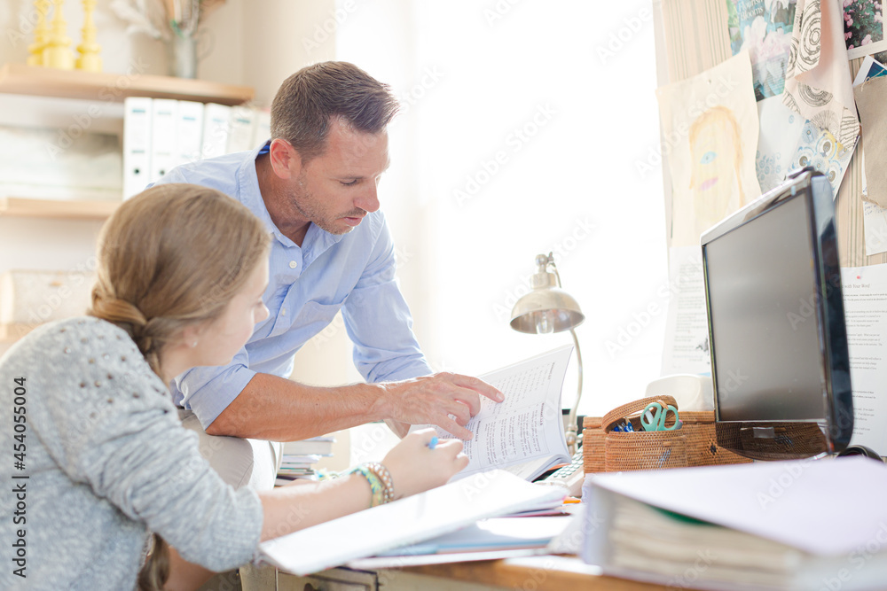 Father helping teenage daughter with her homework Father helping teenage daughter with her homework