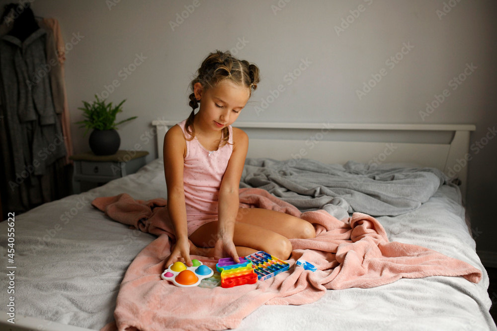 Pretty little girl in pink pajamas laying in her bad at daytime and