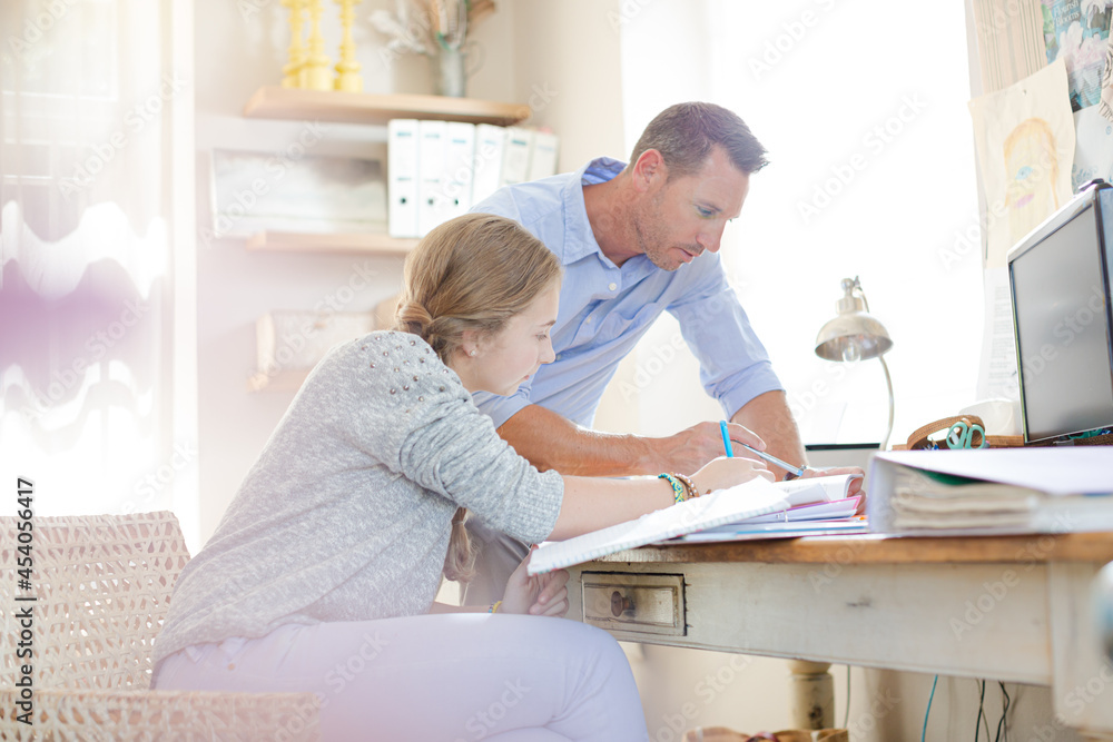 Father helping teenage daughter with her homework