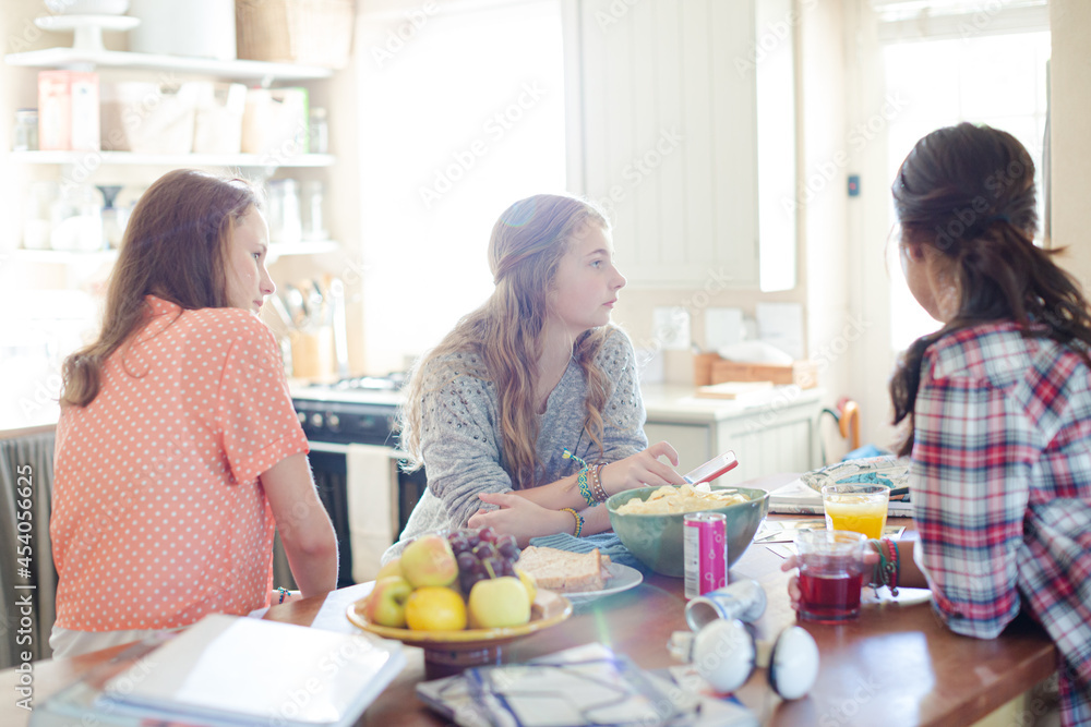 Teenage girls learning at table in kitchen Teenage girls learning at table in kitchen