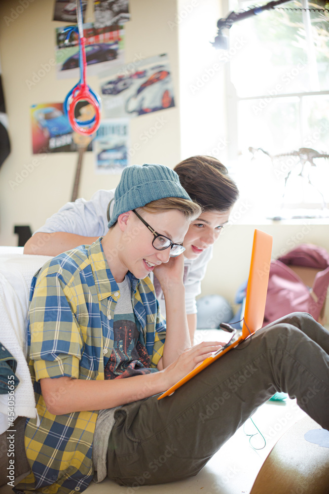 Fototapeta premium Two teenage boys using electronic devices in room
