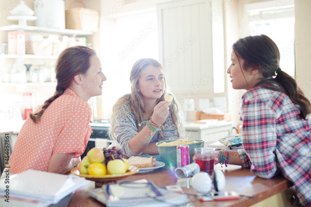 Teenage girls learning at table in kitchen Teenage girls learning at table in kitchen