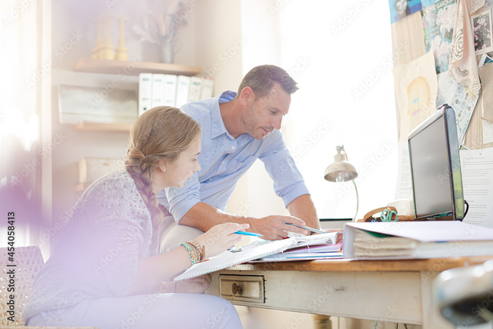 Father helping teenage daughter with her homework Father helping teenage daughter with her homework