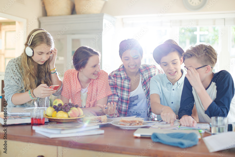 Group of smiling teenagers gathered around table in dining room Group of smiling teenagers gathered around table in dining room