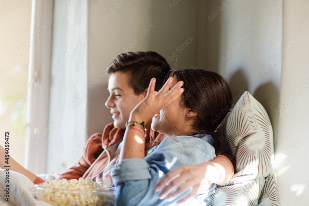 Teenage couple lying in bed and eating popcorn Teenage couple lying in bed and eating popcorn