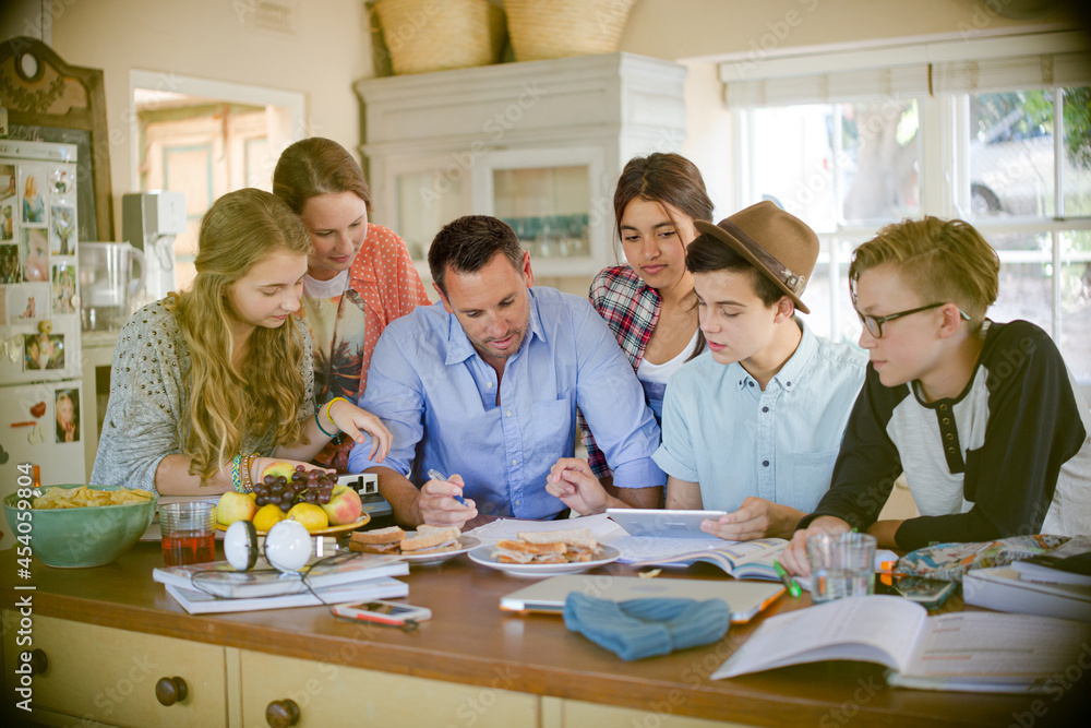 Teenagers with mid adult man sitting at table in dining room Teenagers with mid adult man sitting at table in dining room