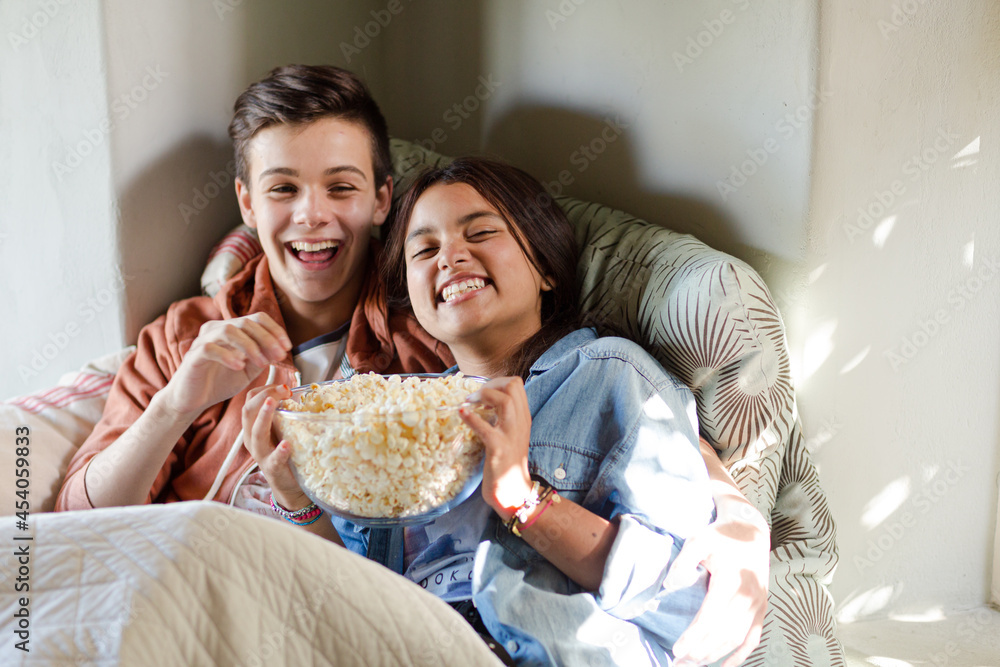 Teenage couple lying in bed and watching tv Teenage couple lying in bed and watching tv