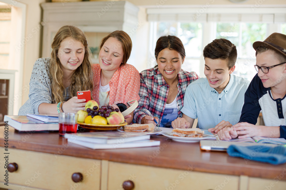 Group of smiling teenagers gathered around table in dining room Group of smiling teenagers gathered around table in dining room