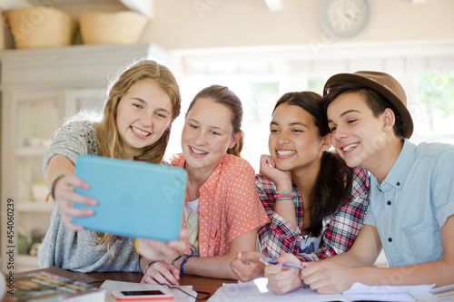 Group of smiling teenagers taking selfie in dining room
