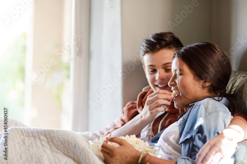 Teenage couple lying in bed and eating popcorn