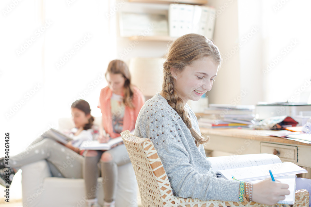 Three teenage girls doing homework in room Three teenage girls doing homework in room