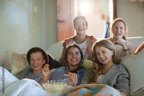 Group of teenagers having fun while watching tv on sofa