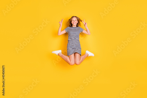 Full length portrait of excited cheerful person fingers show v-sign have good mood isolated on yellow color background © deagreez
