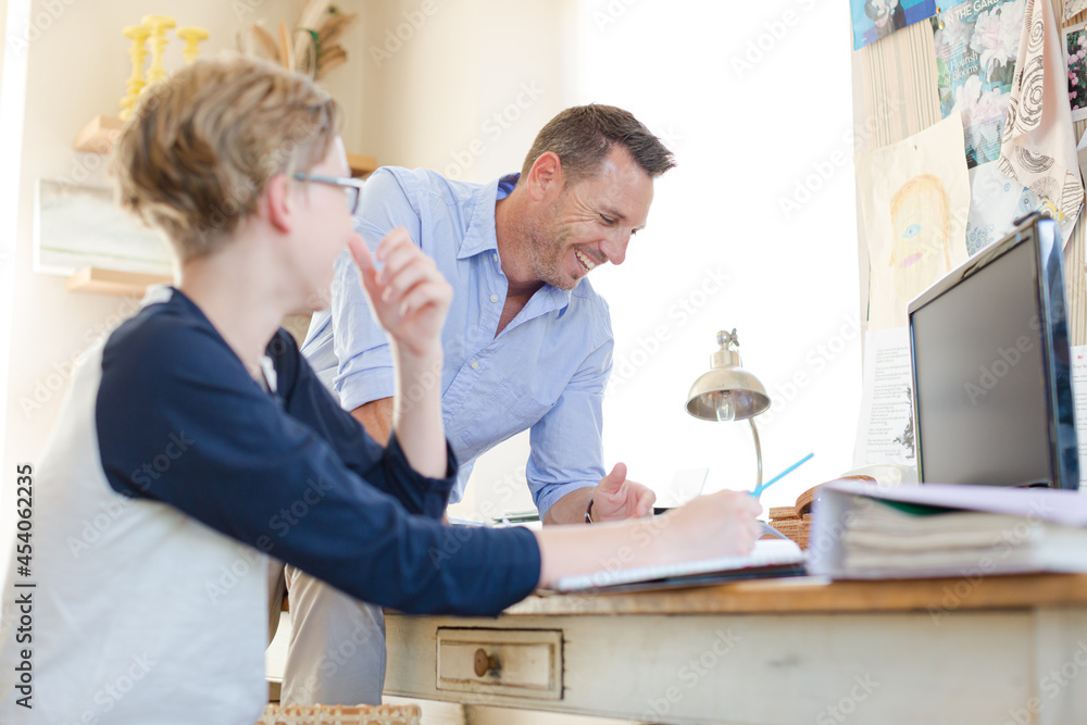 Obraz premium Father helping teenage son doing his homework in room