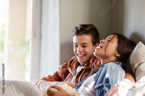 Teenage couple lying in bed and eating popcorn