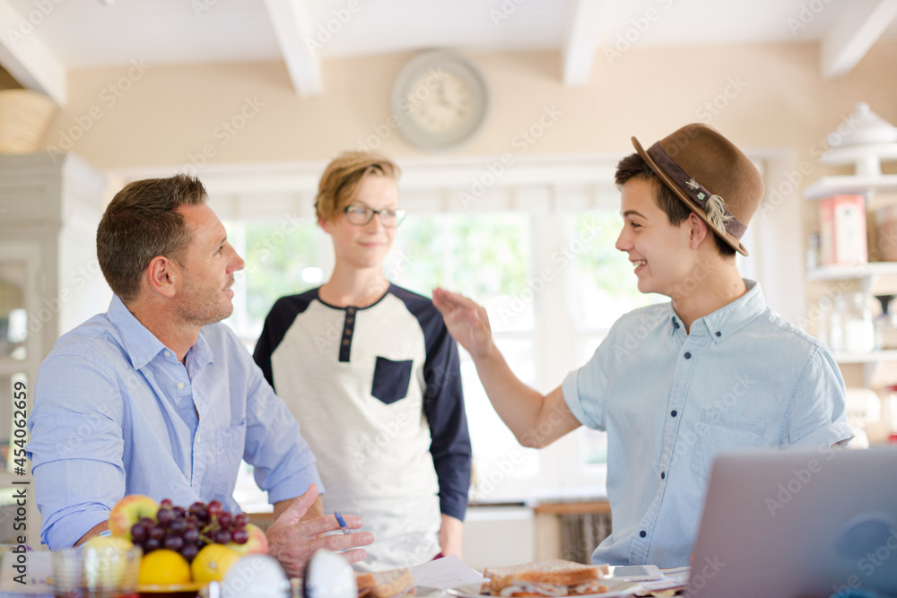 Mid adult man watching teenage boys doing high five Mid adult man watching teenage boys doing high five