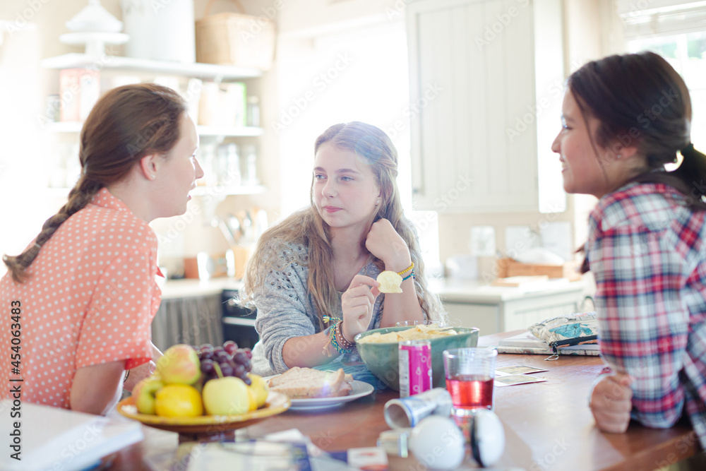 Teenage girls learning at table in kitchen Teenage girls learning at table in kitchen
