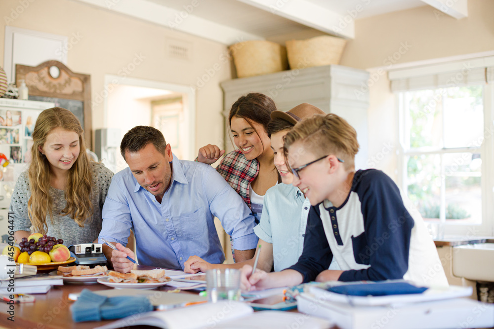 Teenagers with mid adult man sitting at table in dining room Teenagers with mid adult man sitting at table in dining room