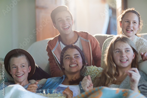 Group of teenagers having fun while watching tv on sofa