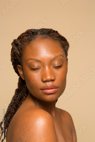 Studio shot of shirtless woman with braided hair and eyes closed