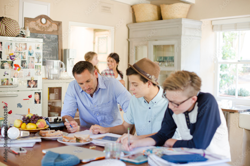 Teenagers with mid adult man sitting at table in dining room Teenagers with mid adult man sitting at table in dining room
