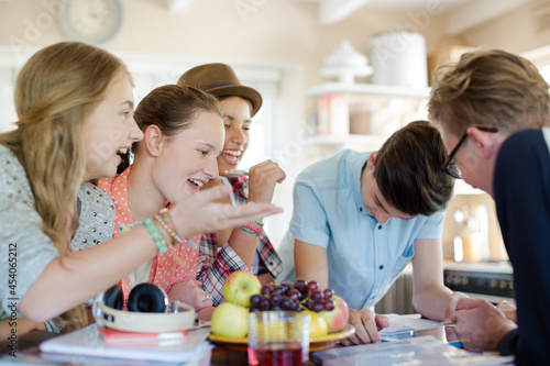 Group of teenagers using together digital tablet at table in kitchen
