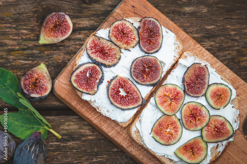Cream cheese with figs on bread served on wooden board