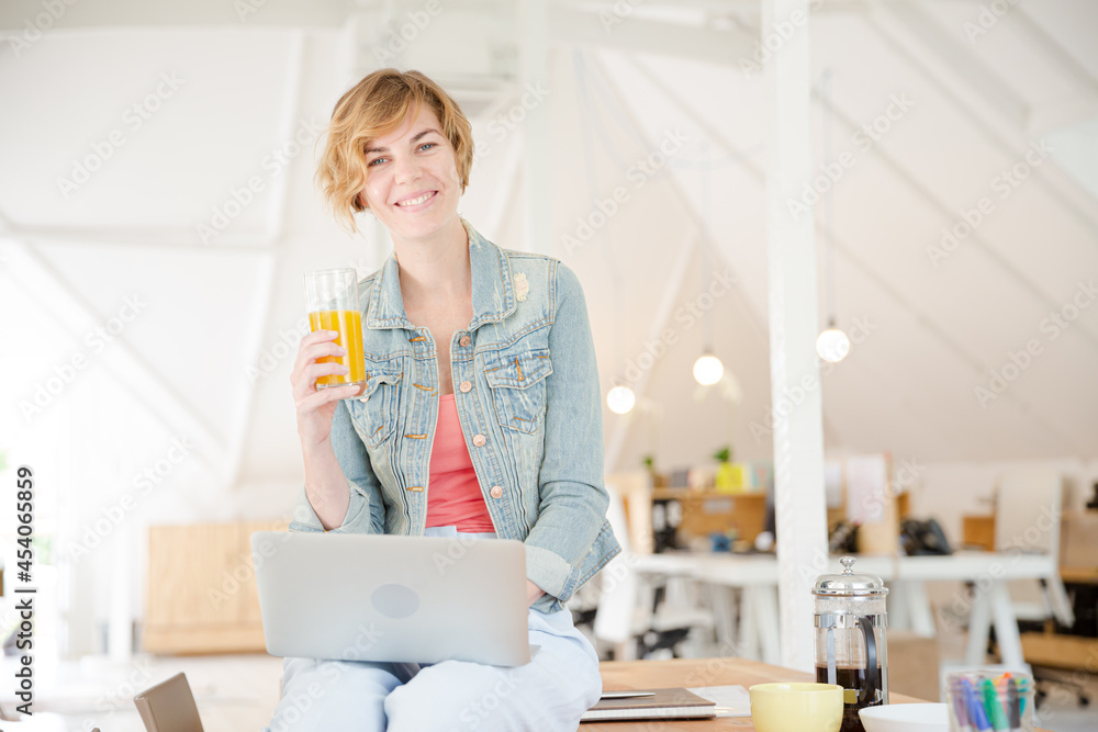 Portrait of woman sitting at desk with laptop in office Portrait of woman sitting at desk with laptop in office