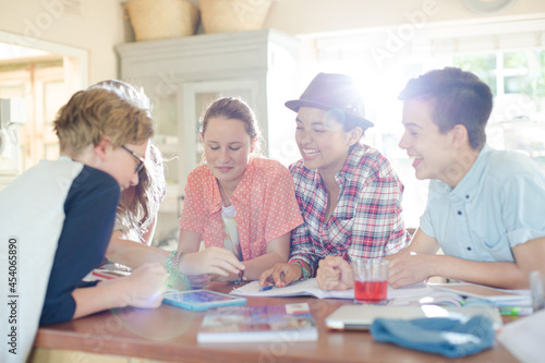 Group of teenagers using together digital tablet at table in kitchen