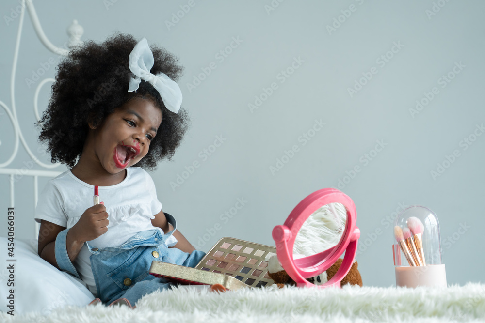 modul hjerne Milepæl Little African girl playing makeup with mother's cosmetics. Adorable kid  painting her lips with red lipstick and looking in the mirror with joy in  bedroom at home Photos | Adobe Stock