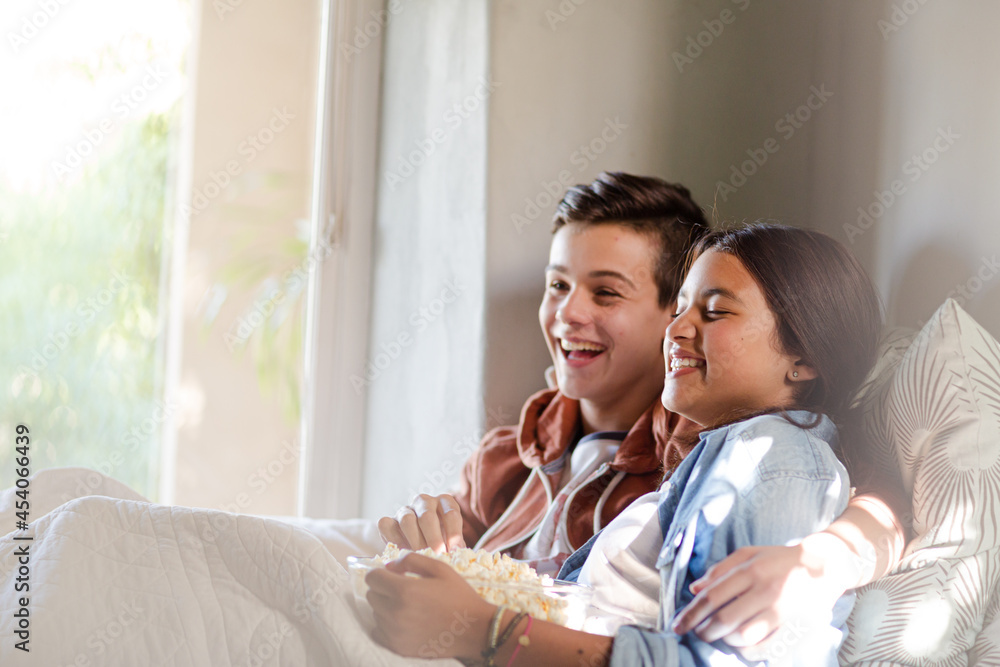 Teenage couple lying in bed and eating popcorn Teenage couple lying in bed and eating popcorn