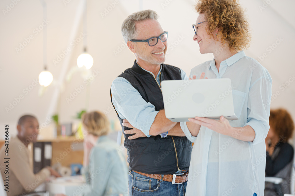 Fototapeta premium Portrait of man and woman with laptop, smiling in office