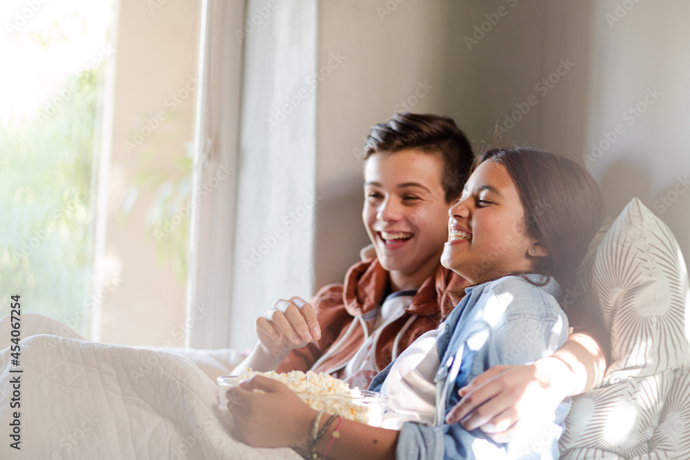 Teenage couple lying in bed and eating popcorn Teenage couple lying in bed and eating popcorn