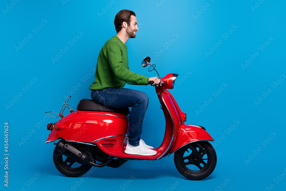 Fototapeta premium Full size profile side photo of smiling good mood man ride red moped travel freedom isolated on blue color background