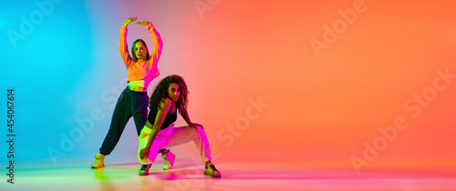 Foto Two beautiful stylish hip-hop female dancers on colorful gradient background in