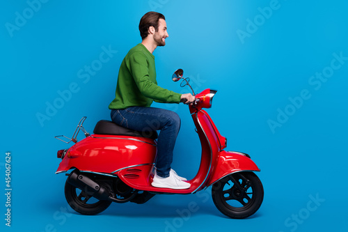 Full size profile side photo of smiling good mood man ride red moped travel freedom isolated on blue color background