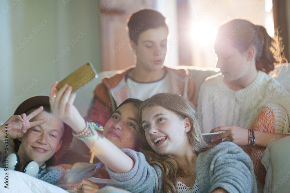 Group of teenagers taking selfie on sofa in living room