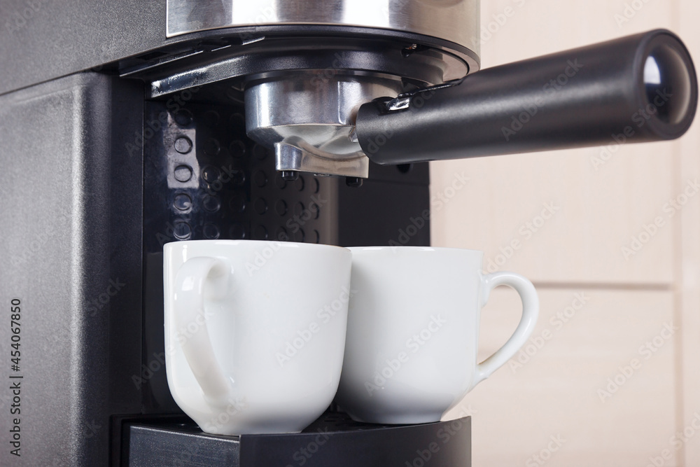 Two white cups for coffee under horn coffee maker. Two white cups for coffee under horn coffee maker.