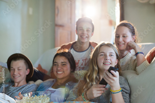 Group of teenagers having fun while watching tv on sofa
