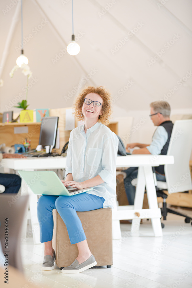 Woman using laptop and smiling in office Woman using laptop and smiling in office