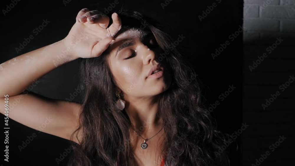 Beautiful woman gently wipes her forehead with a hand in flour while cooking, flour on the girl's face in slow motion Beautiful woman gently wipes her forehead with a hand in flour while cooking, flour on the girl's face in slow motion