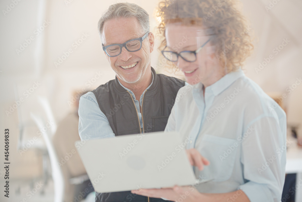 Portrait of man and woman with laptop, smiling in office