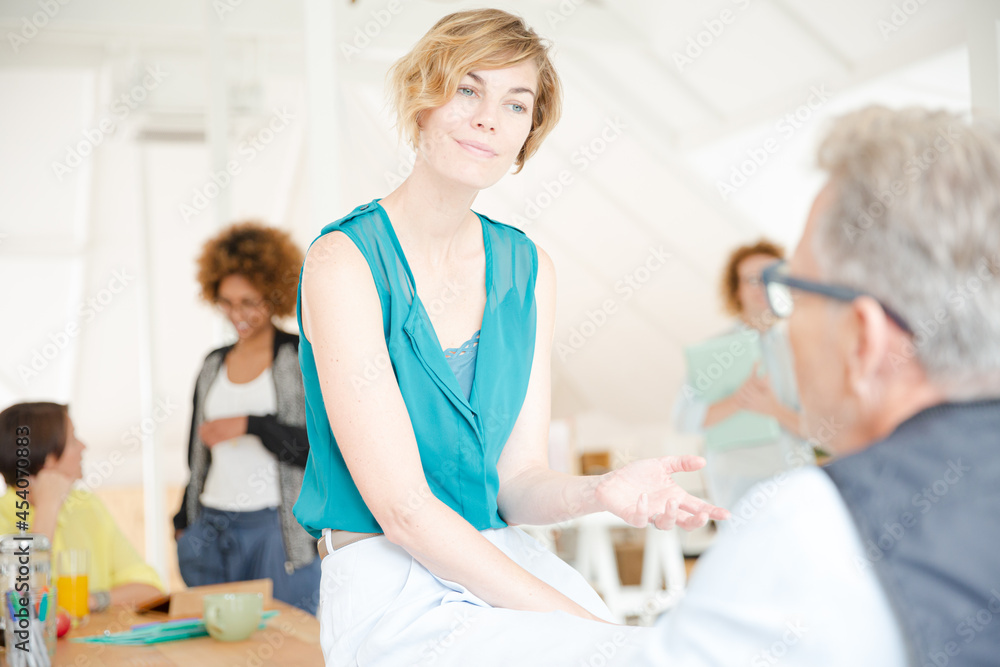 Man and woman sitting in office,smiling and talking Man and woman sitting in office,smiling and talking