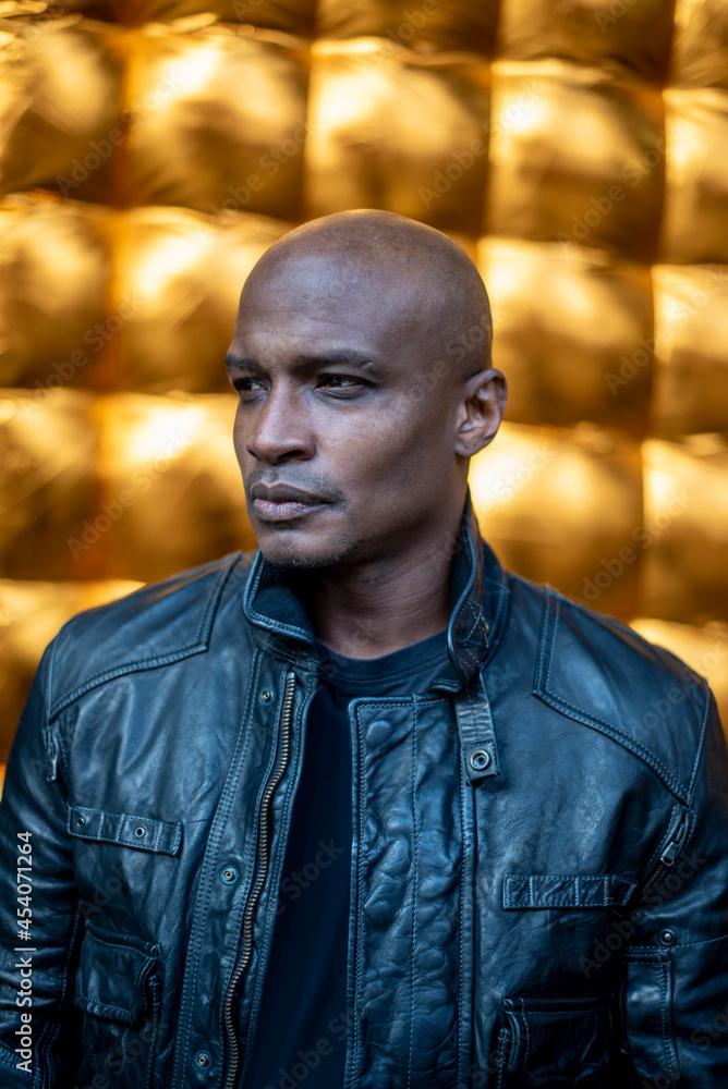 Man in leather jacket against golden textured surface