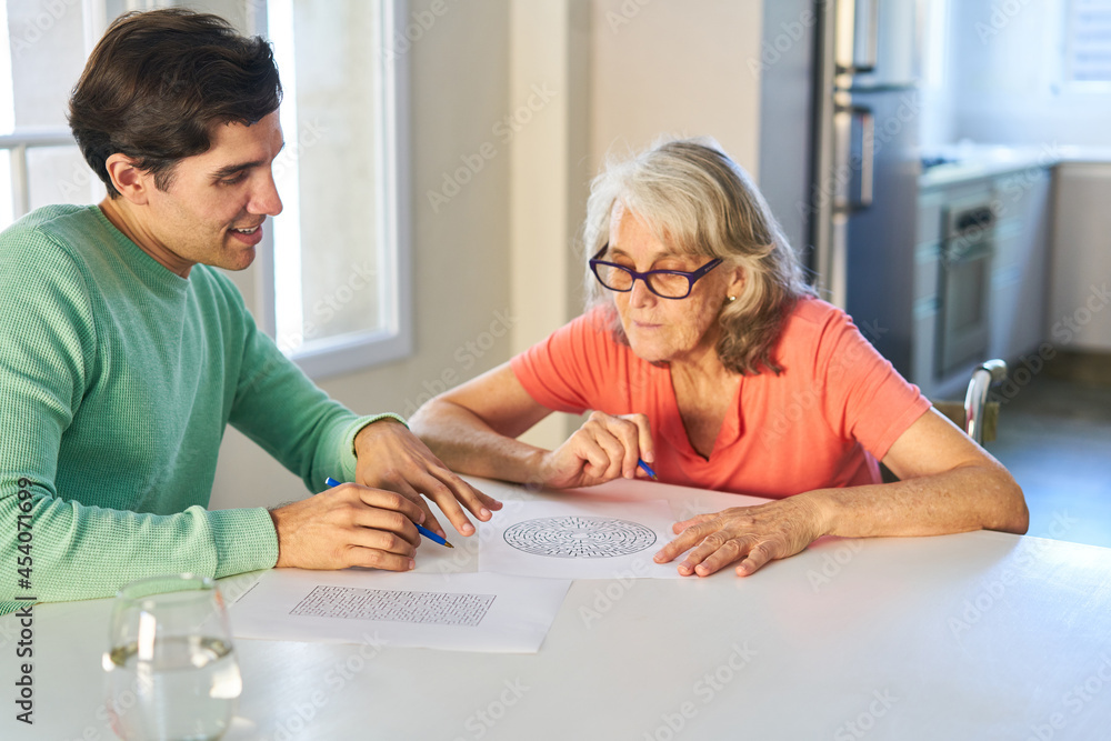 Man helps elderly woman with dementia with memory training Man helps elderly woman with dementia with memory training