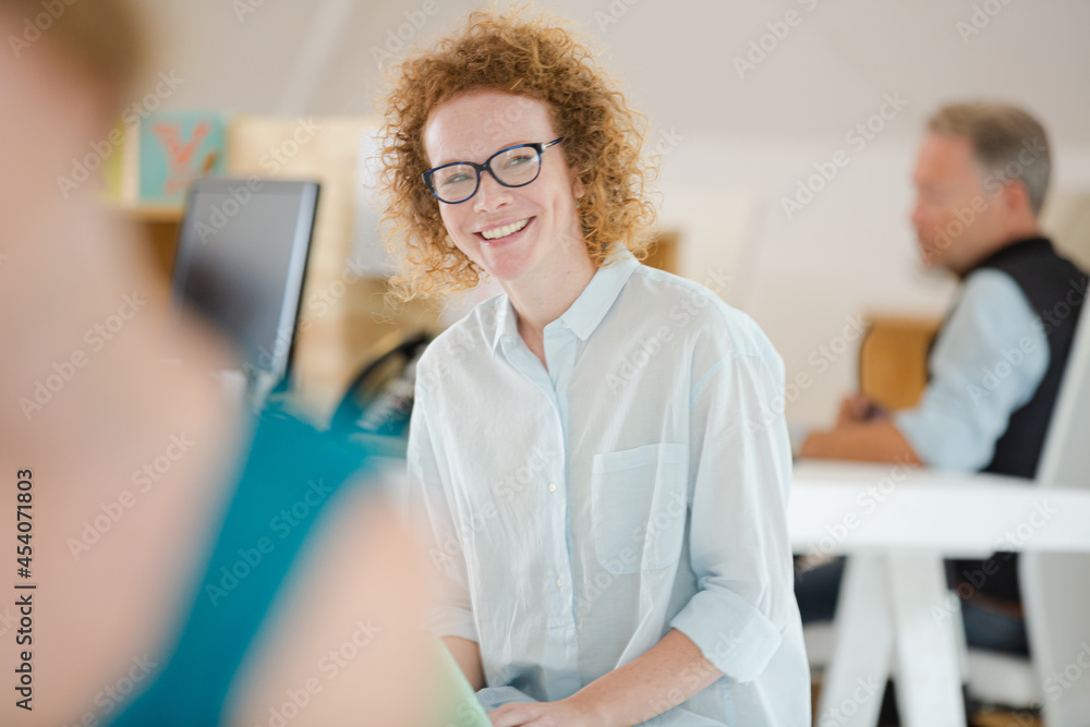 Fototapeta premium Woman using laptop and smiling in office