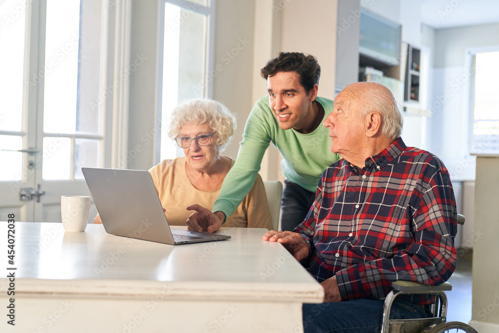 Son helps senior parents with video call on laptop