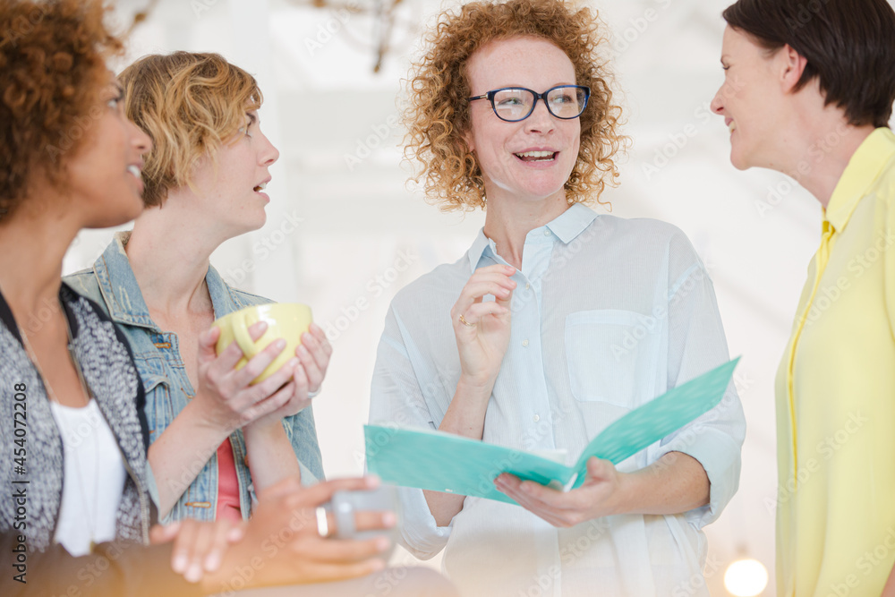 Women with coffe cup talking in office Women with coffe cup talking in office